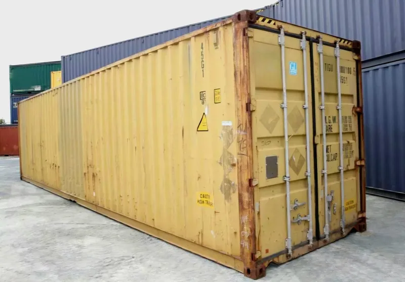 Yellow 12m shipping container with surface rust and dents along the corrugated side