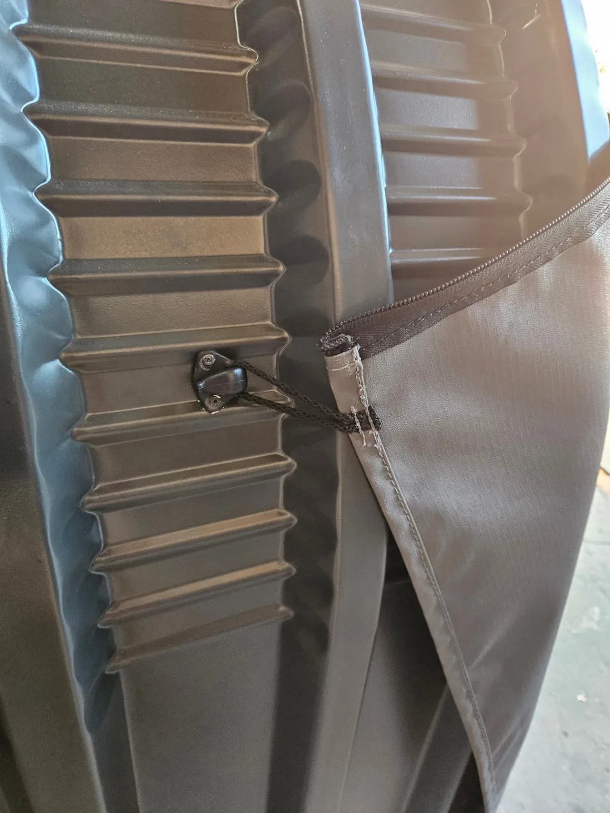 Close-up of the charcoal corrugated shed frame with a canvas cover clipped to a fixing point by a cord