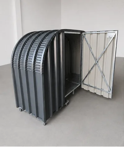 Firewood shed with protective backing and a hinged steel lockable door, keeping the wood store secure