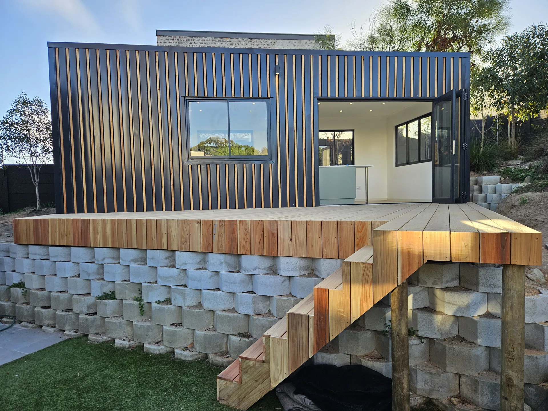 One Bedroom Pod viewed from the garden, showing its vertical cladding, glazed sliding doors and raised timber deck