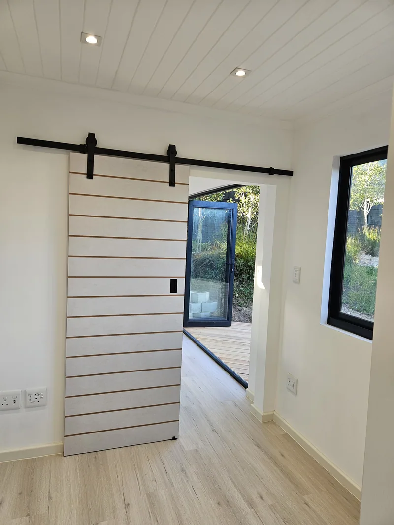 One Bedroom Pod interior viewed through an open barn door toward the glazed deck doors