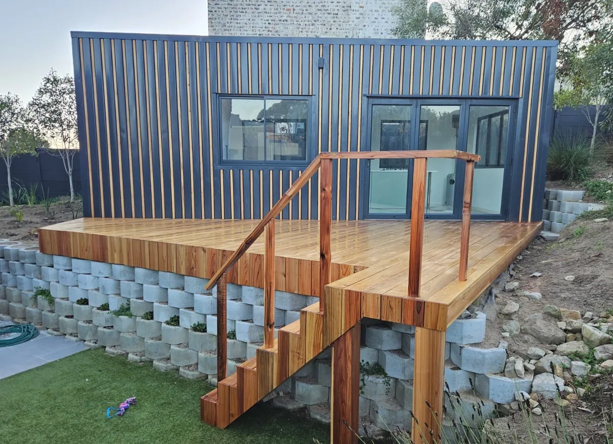 Modular home with vertical timber and steel cladding, a timber deck and staircase on a concrete block base
