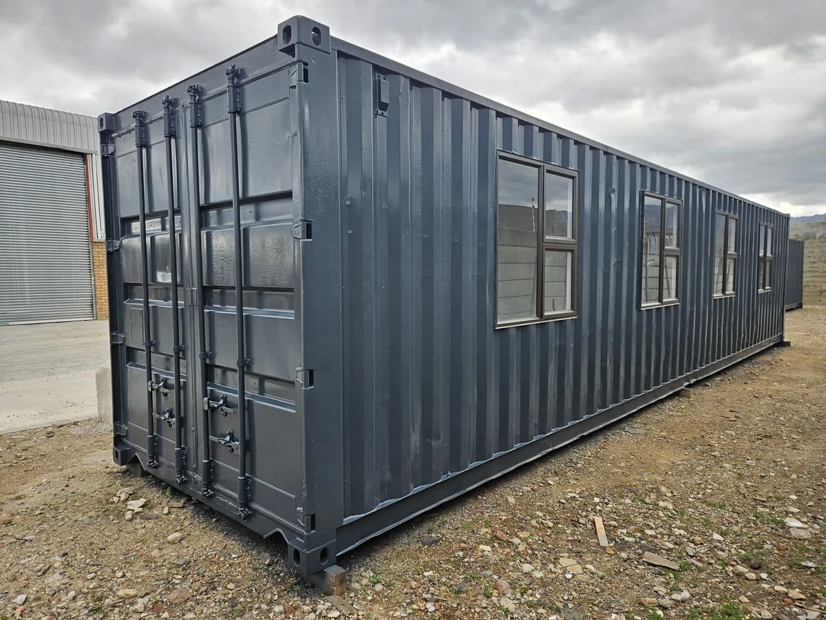 Dark grey 12m container office with three windows, standing on a gravel site