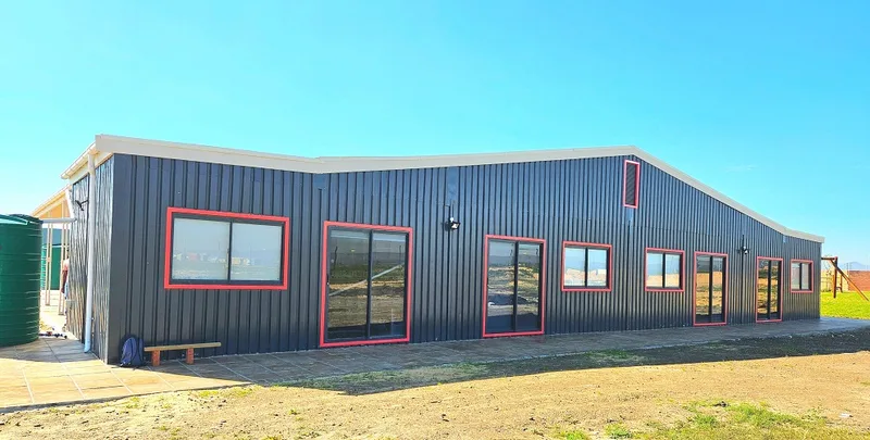 Side elevation of the school showing the raked roofline and a row of red-framed windows