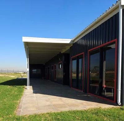 Covered walkway running along the classroom block with sliding doors opening onto a paved terrace