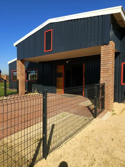 Entrance to the school with brick columns, double-height gable and a fenced forecourt
