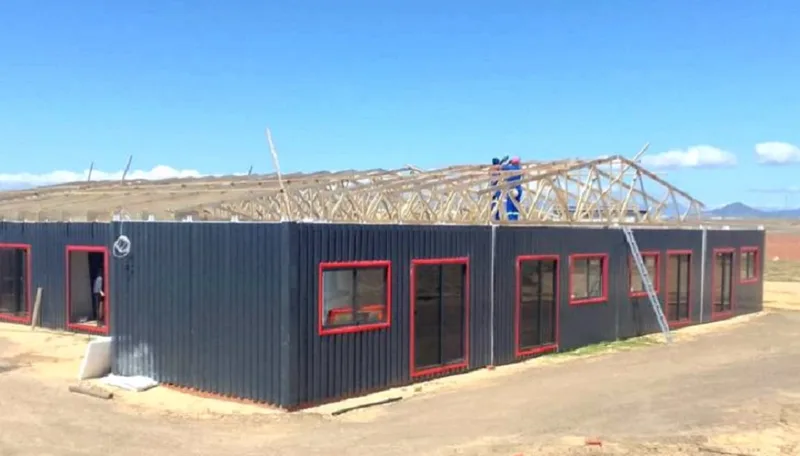 Roof trusses being installed over the completed steel-clad classroom walls during construction