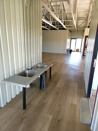 Corridor with a double basin unit against ribbed steel wall panels leading into the hall