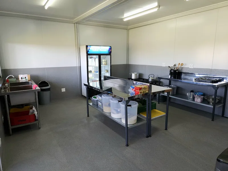 Kitchen fitted with stainless steel prep tables, sink, gas hob and a display fridge