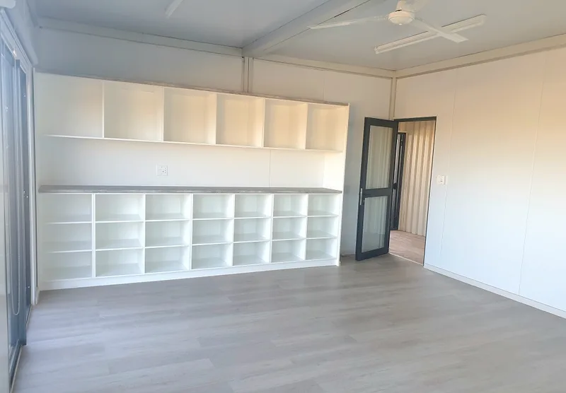 Room with full-length cubby shelving, counter top and ceiling fan
