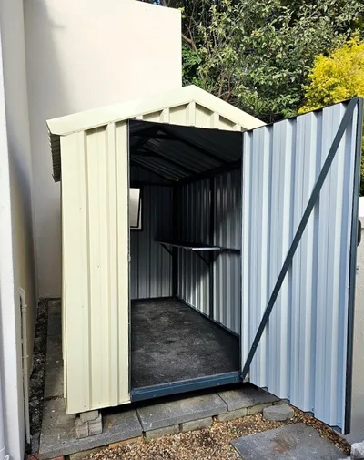 Garden shed with the door open showing the internal shelf and steel-lined walls