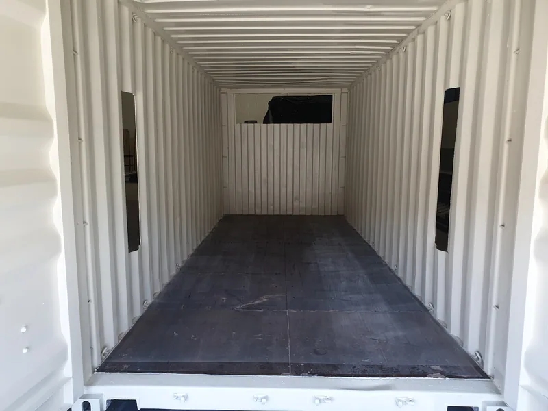 Empty interior of a white-lined container with a dark rubber floor and louvred vents in the side walls
