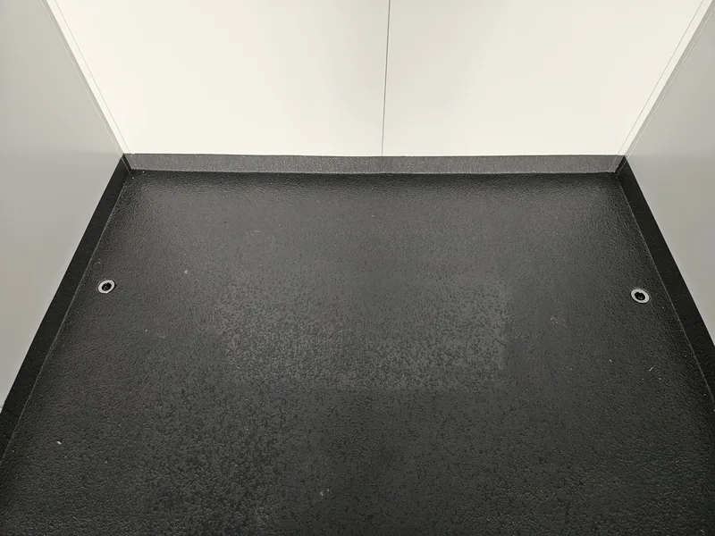 Empty container interior with a black non-slip floor coating and coved white walls