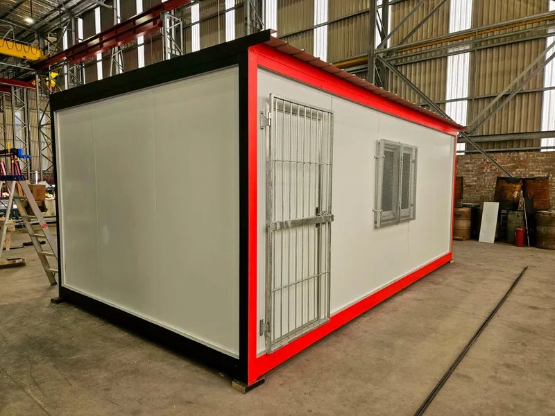 White modular kitchen unit with red trim inside a fabrication workshop