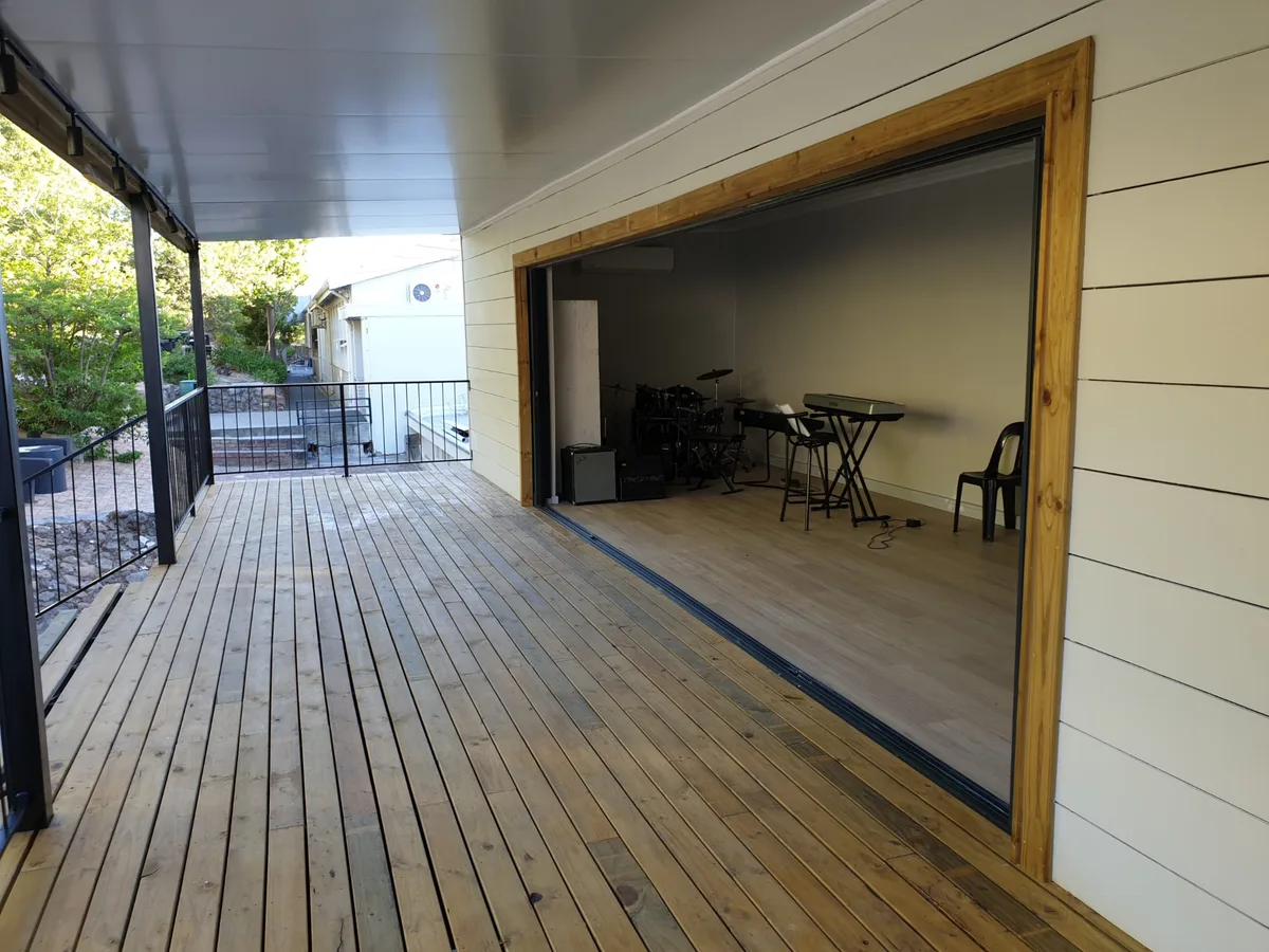 Covered deck running alongside the music room with the sliding doors open onto the practice space