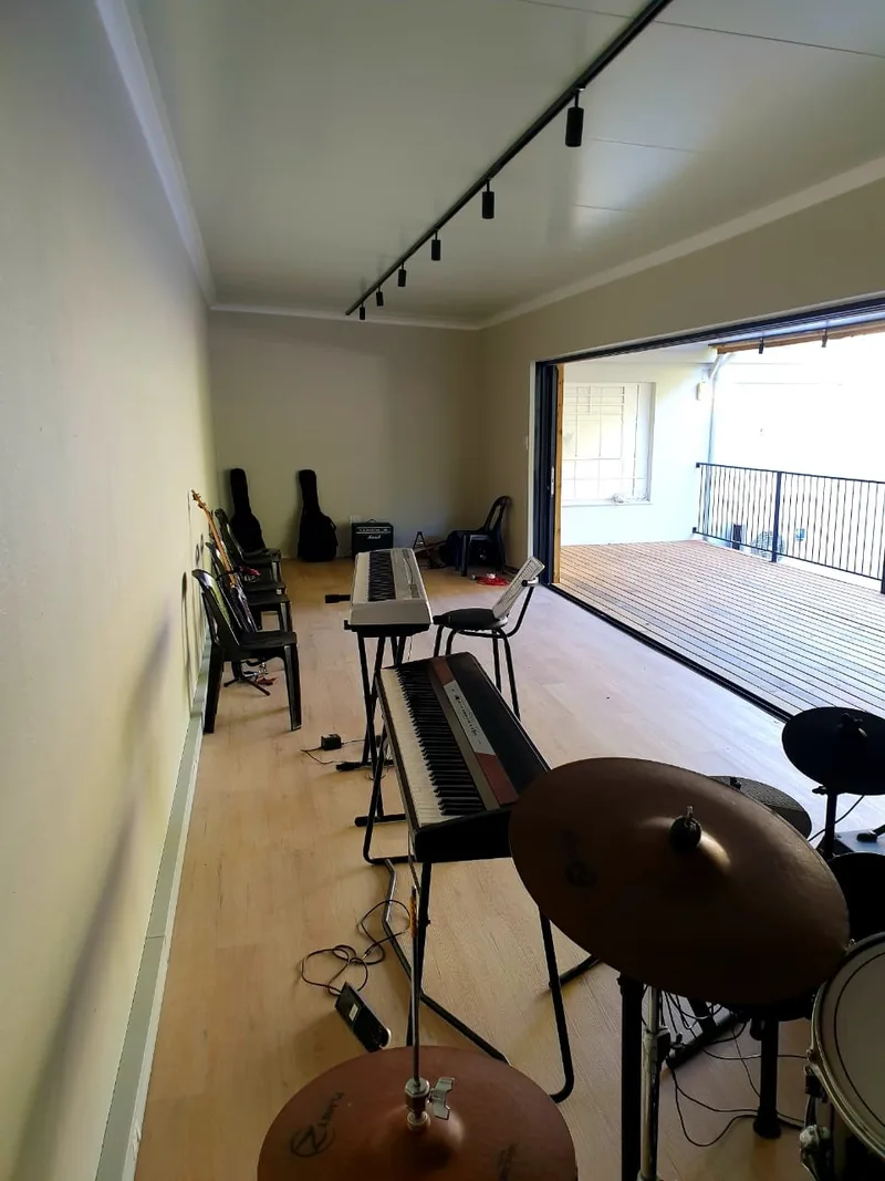 Interior of the music room with track lighting, keyboards and a drum kit set up