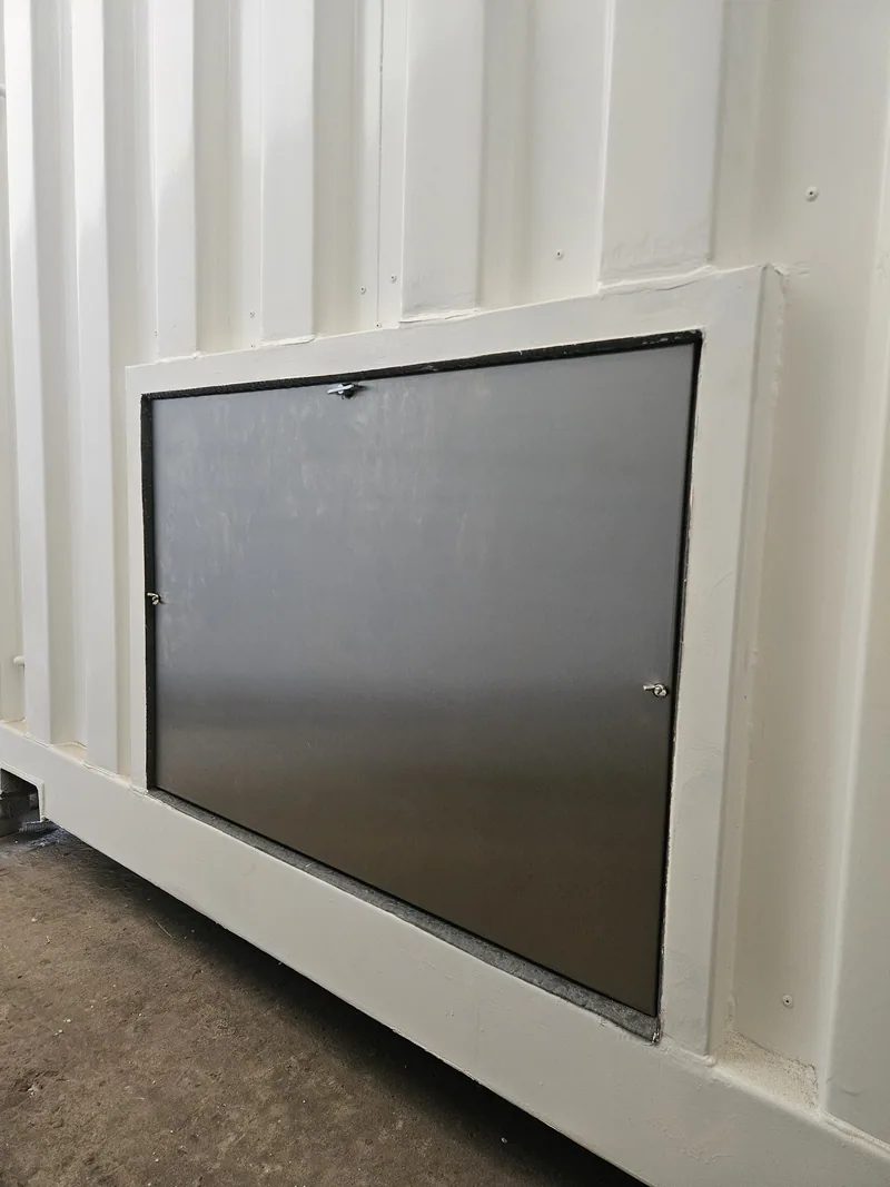 Hinged white service hatch set into the corrugated side wall of a container